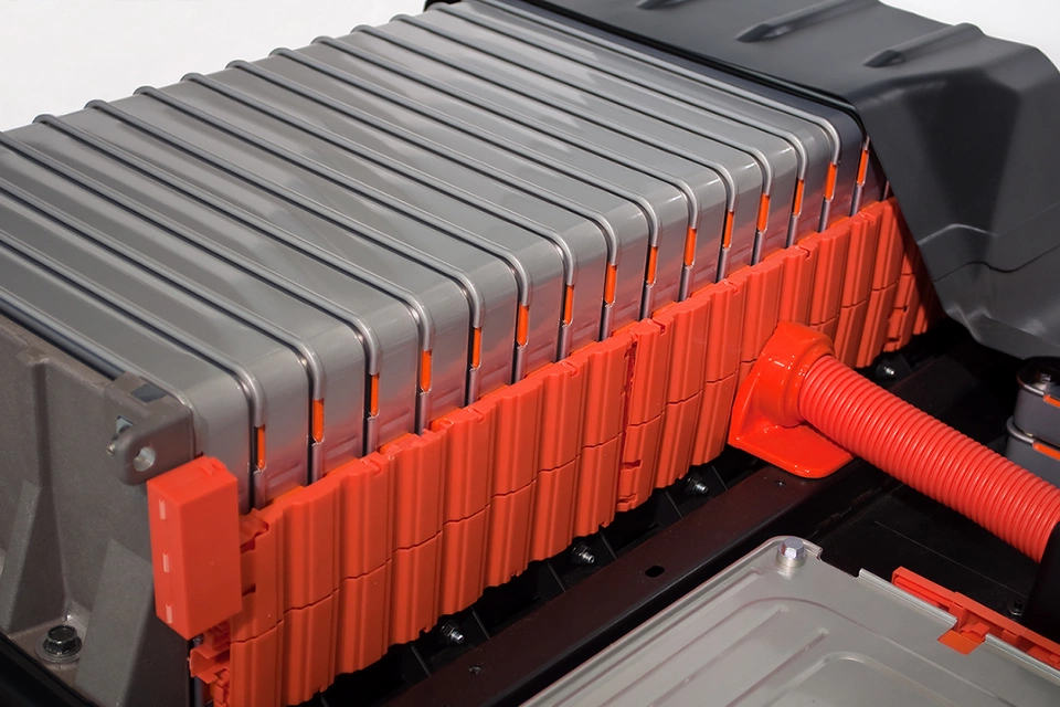 Batteries loaded in a row on an electric car. Each battery pack is stacked in an orange plastic case. 