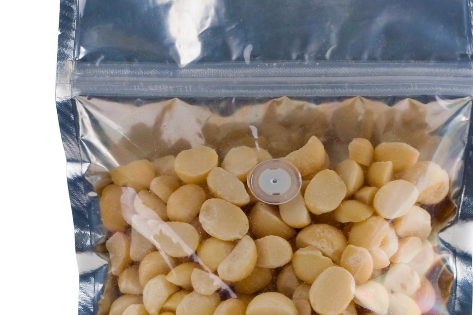 A zip top foil pouch filled with halved macadamis nuts.  Ready for your label design or logo.