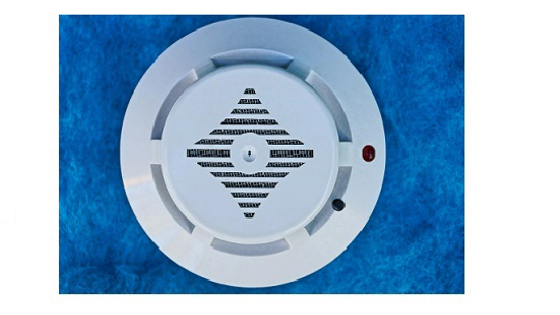 one white round plastic fire alarm device on the blue wall